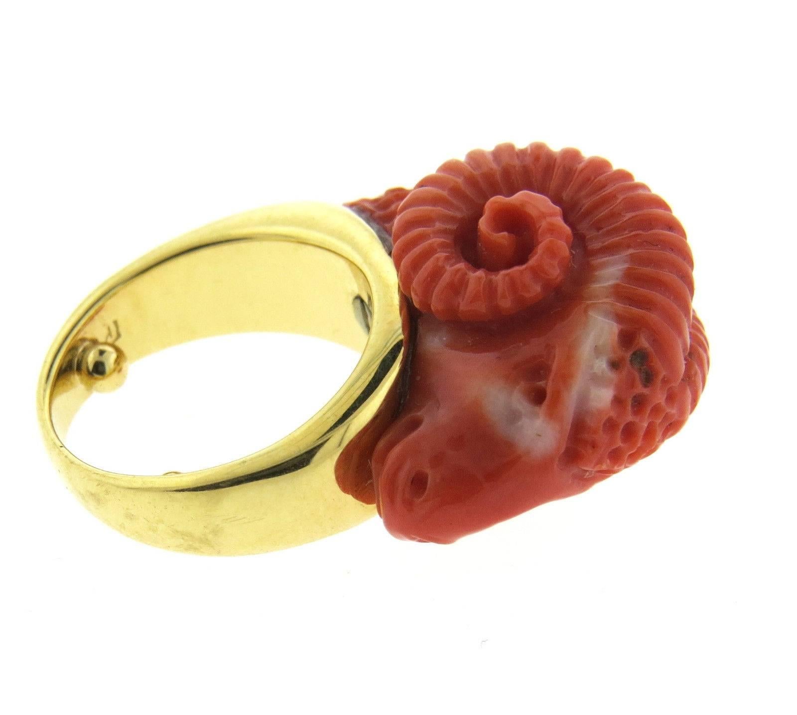 An 18k yellow gold ring set with a carved coral ram's head.  The ring is a size 4 (sizing balls can be removed to increase size) ram's head measures 14mm x 22mm and sits approx. 15mm from the top of the finger.  The weight of the piece is 13.8 grams.