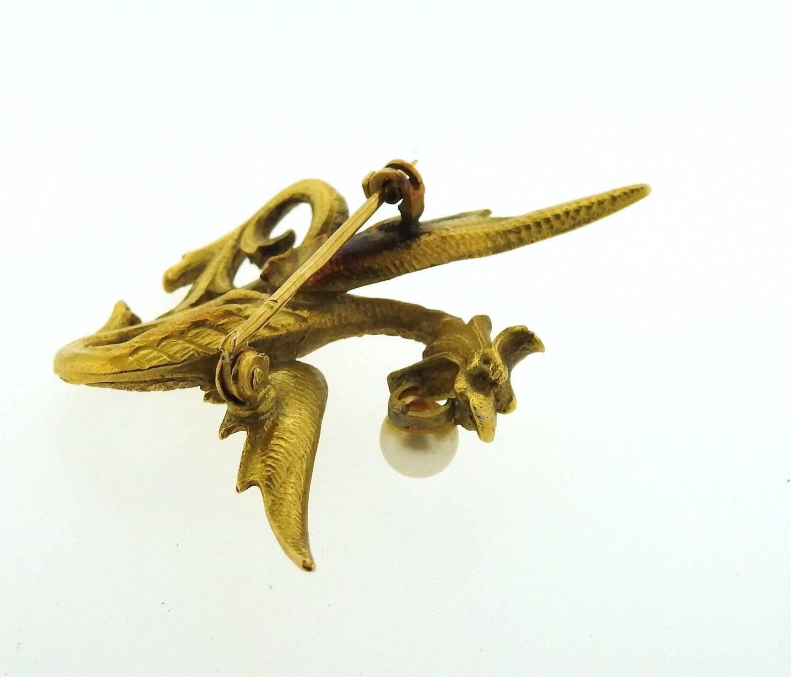 An 18k yellow gold dragon pin set with a 5.6mm pearl.  The brooch measures 48mm x 35mm and weighs 16 grams. 