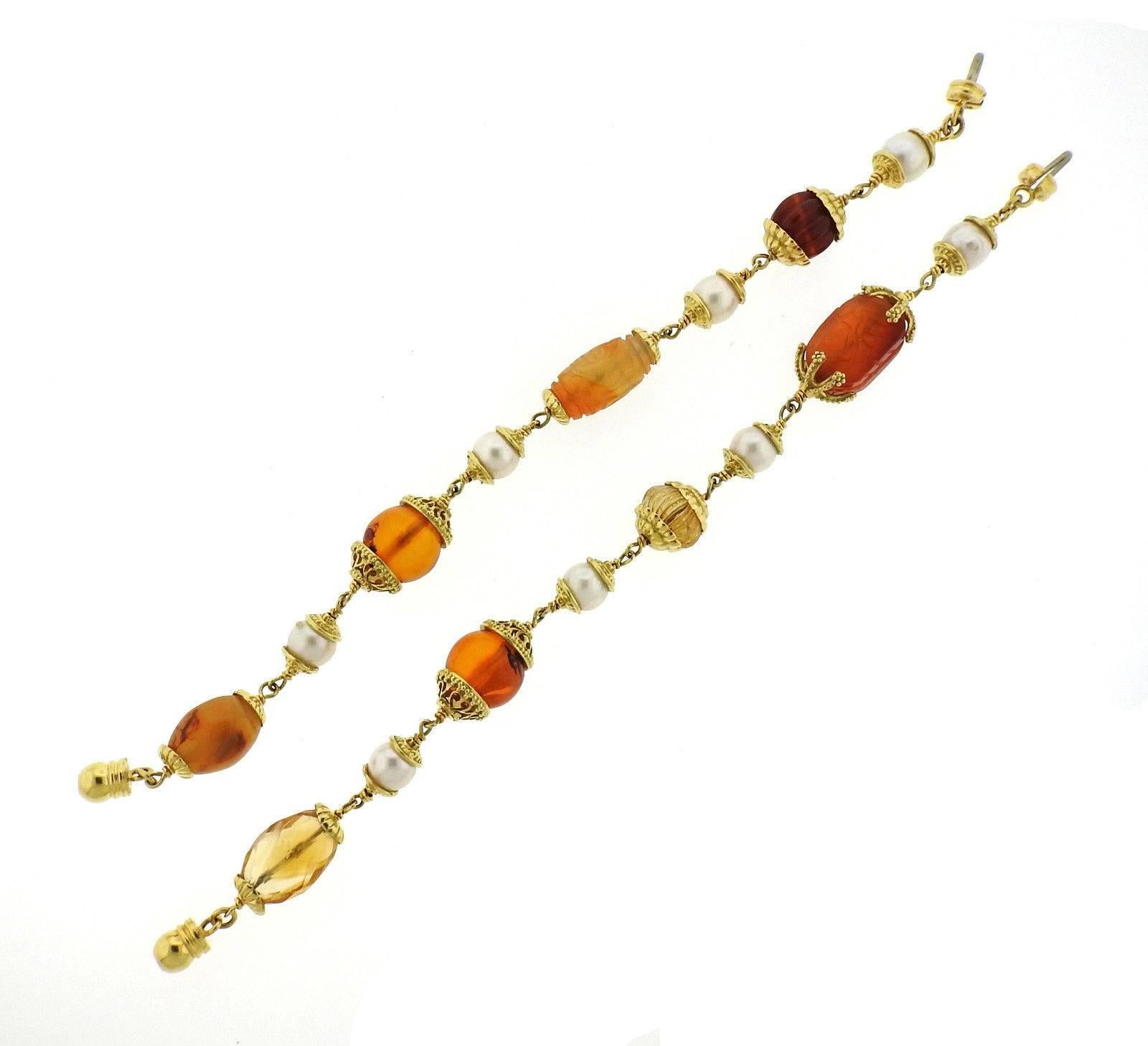 A pair of 18k yellow gold bracelets set with multi color gemstones and 8.7mm pearls. The bracelets are each 8 1/8