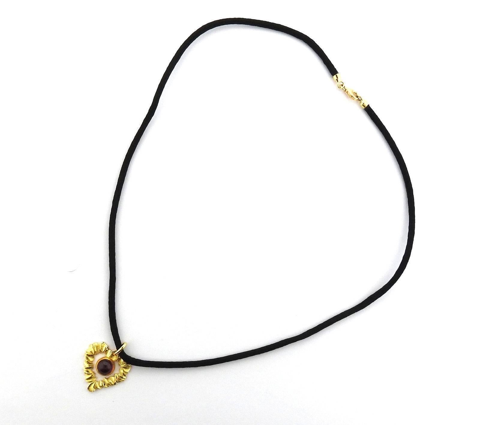 An 18k yellow gold heart pendant set with a 2.10ct rubbellite cabochon, suspended on a black cord.  The necklace is 17 5/8