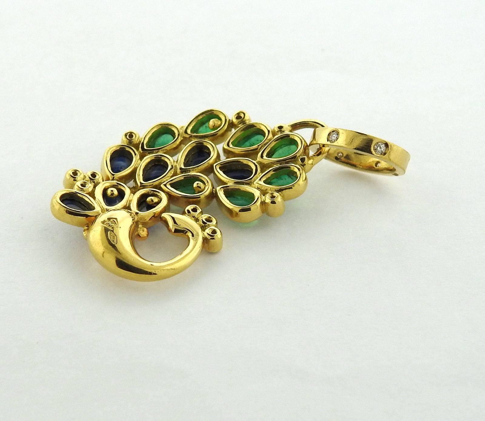 An 18k yellow gold peacock pendant set with sapphires, emeralds, and approximately 0.13ctw of G/VS diamonds. The pendant is 35mm long without bale x 26mm wide, bale - 10mm x 13mm.  The weight of the piece is 11.4 grams.  Marked: Temple mark, 750. 