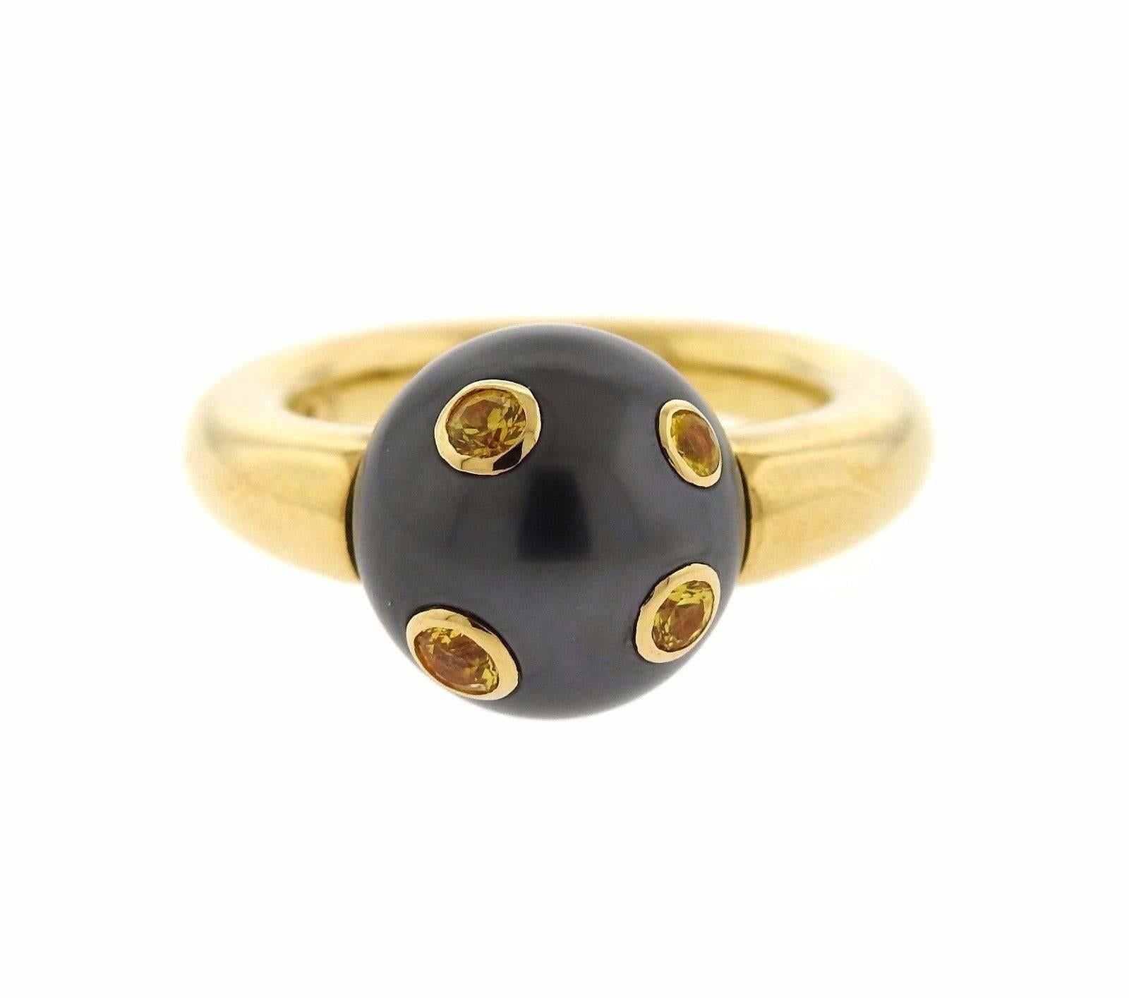 An 18k yellow gold ring set with a 12.5mm Tahitian pearl and yellow sapphires.  The ring is a size 6.25 and the shank is 5.2mm wide.  The weight of the ring is 12.4 grams.  Marked: M, 750 Made in Italy.  Comes with box and papers.  Current retail is