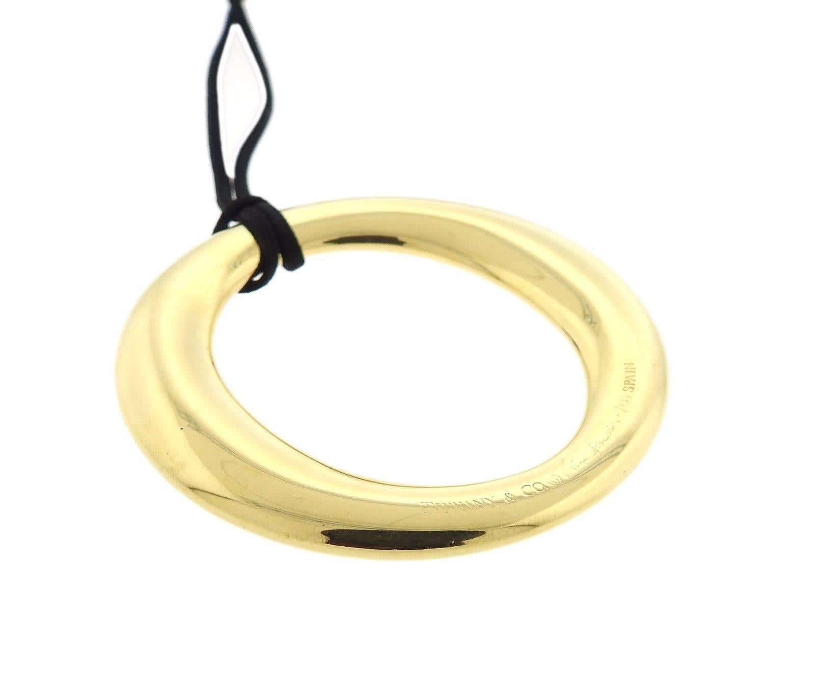 18k gold Sevillana pendant, suspended on a black cord, designed by Elsa Peretti for Tiffany & Co. Cord is 28" long, pendant - 50mm in diameter. Marked: Tiffany & Co, Elsa Peretti, 750, Spain . Weight: 13.1 grams
Comes with pouch 
