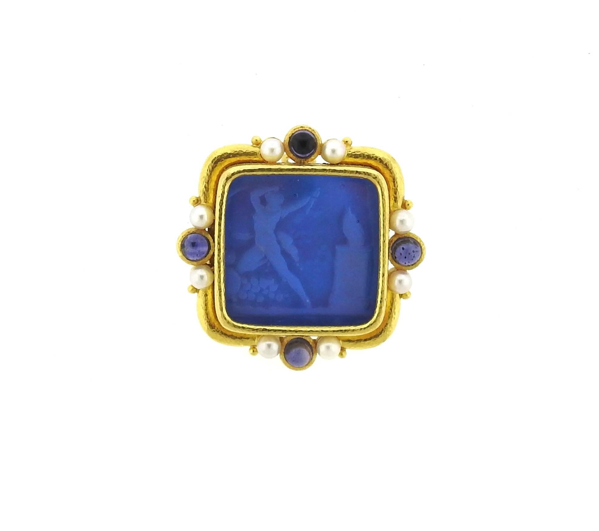 An 18k yellow gold brooch, designed by Elizabeth Locke, featuring Venetian glass intaglio, backed with mother of pearl, surrounded with pearls and blue sapphire cabochons. Brooch has a hidden bale to be worn as a pendant, measures 42mm x 42mm.