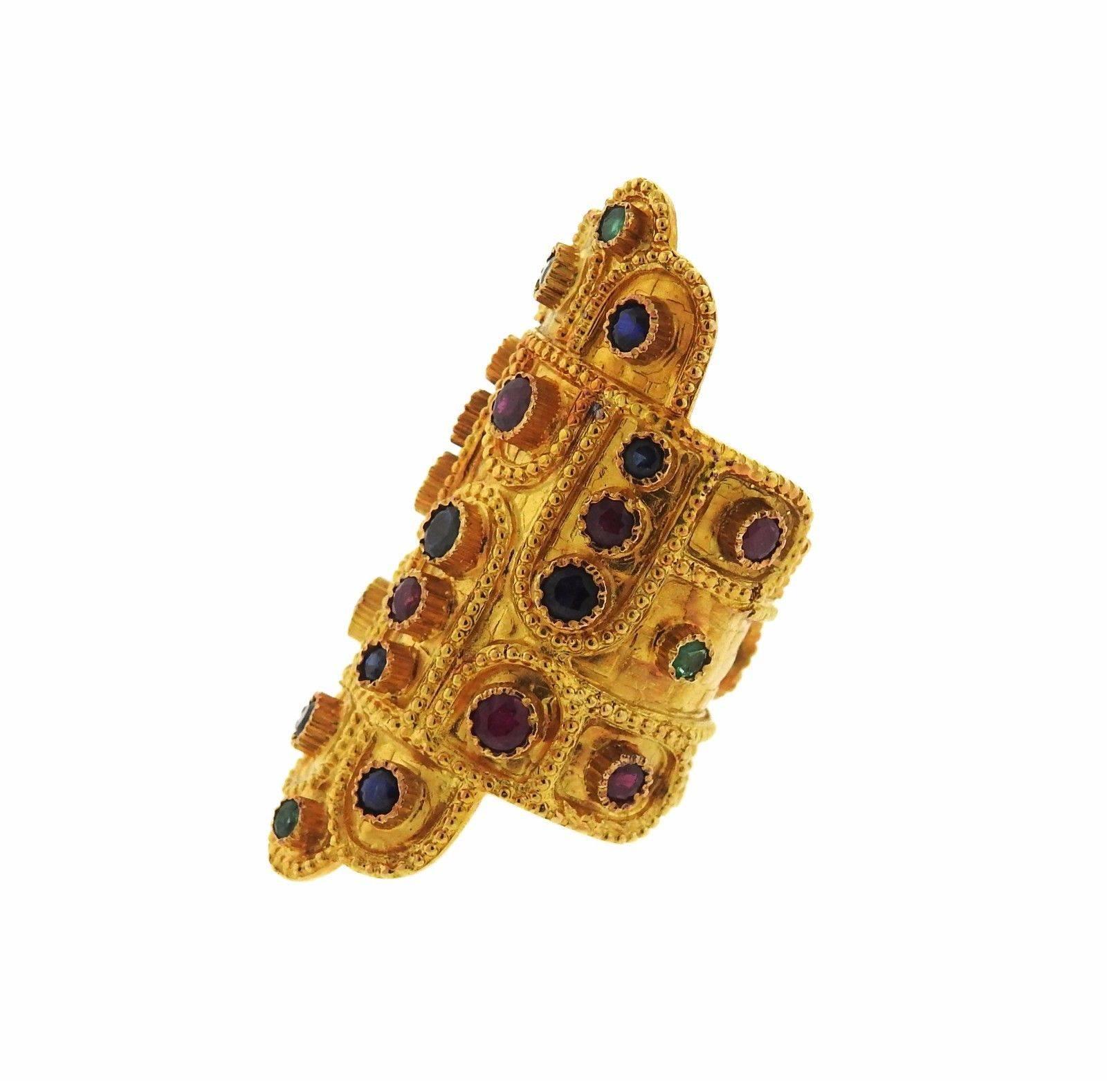 An 18k yellow gold ring set with sapphires rubies and emeralds.  The ring is a size 7.75 (shank is open, slightly flexible). Top measures 45mm at widest point.  The weight of the piece is 18.8 grams.  Marked: A21, Greece, 750, Maker's Mark.