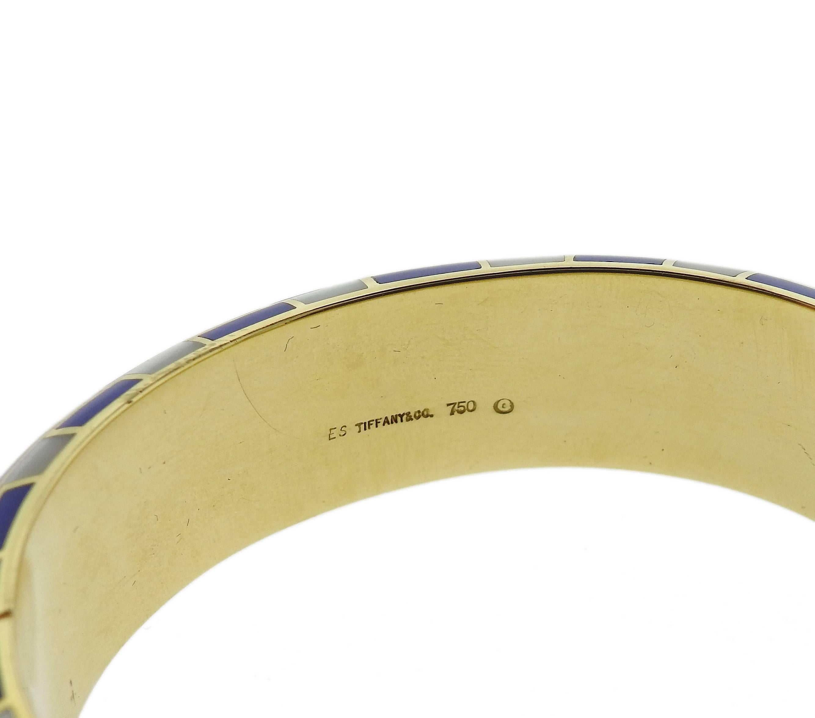 An 18k yellow gold bangle bracelet, crafted by Tiffany & Co, set with inlay dyed blue coral and mother of pearl. Bracelet will fit up to 6 1/2" wrist and is 18mm wide. Marked: TIffany & Co, 750, ES, 346MI. Weight of the piece - 57.3