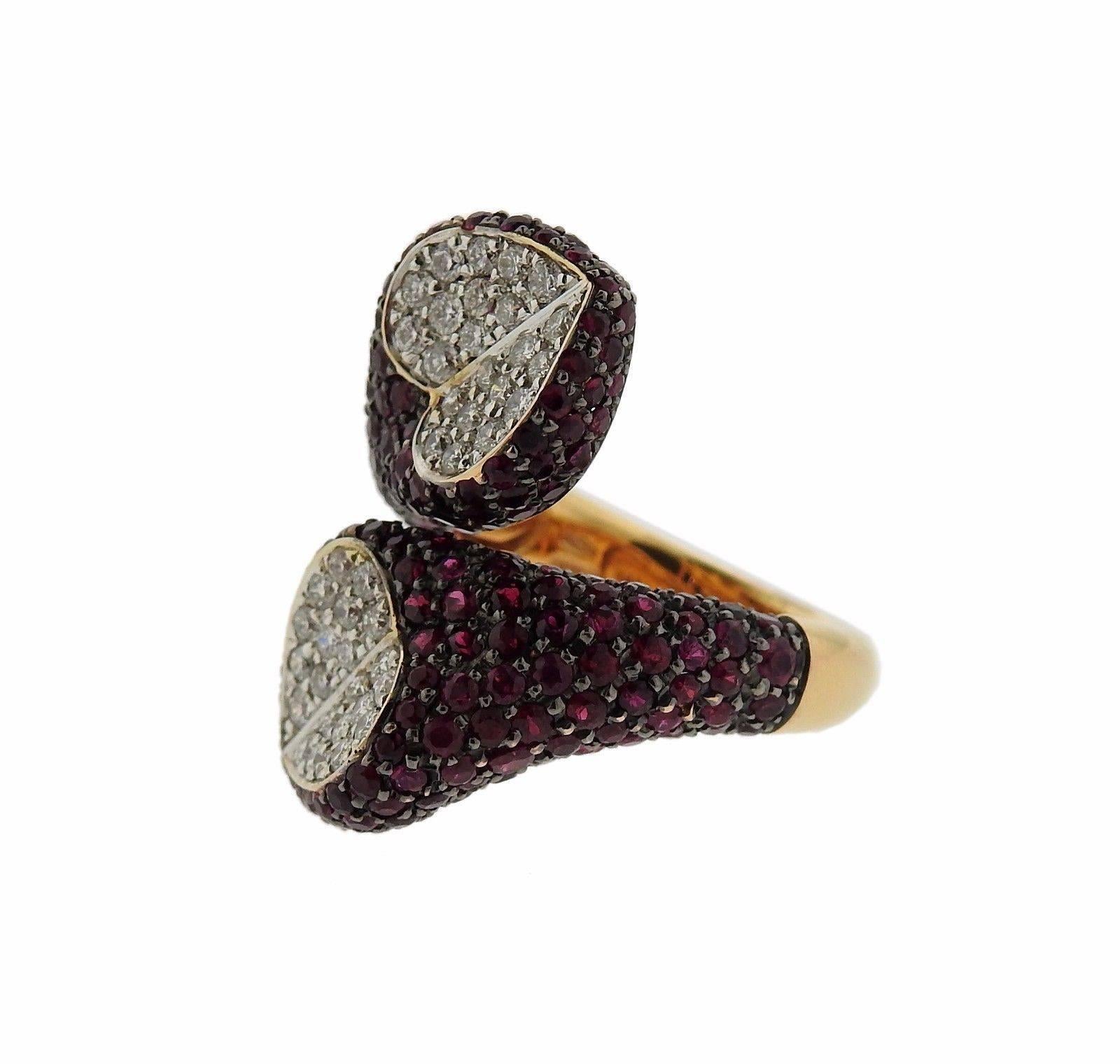 An 18k rose gold bypass ring set with 0.89ctw of G/VS diamonds and approximately 4.77ctw of rubies.  The ring is a size 6 1/4 and is 26mm wide.  Marked: Enigma, 750. The weight of the piece is 12.8 grams.  The retail is $14,500.