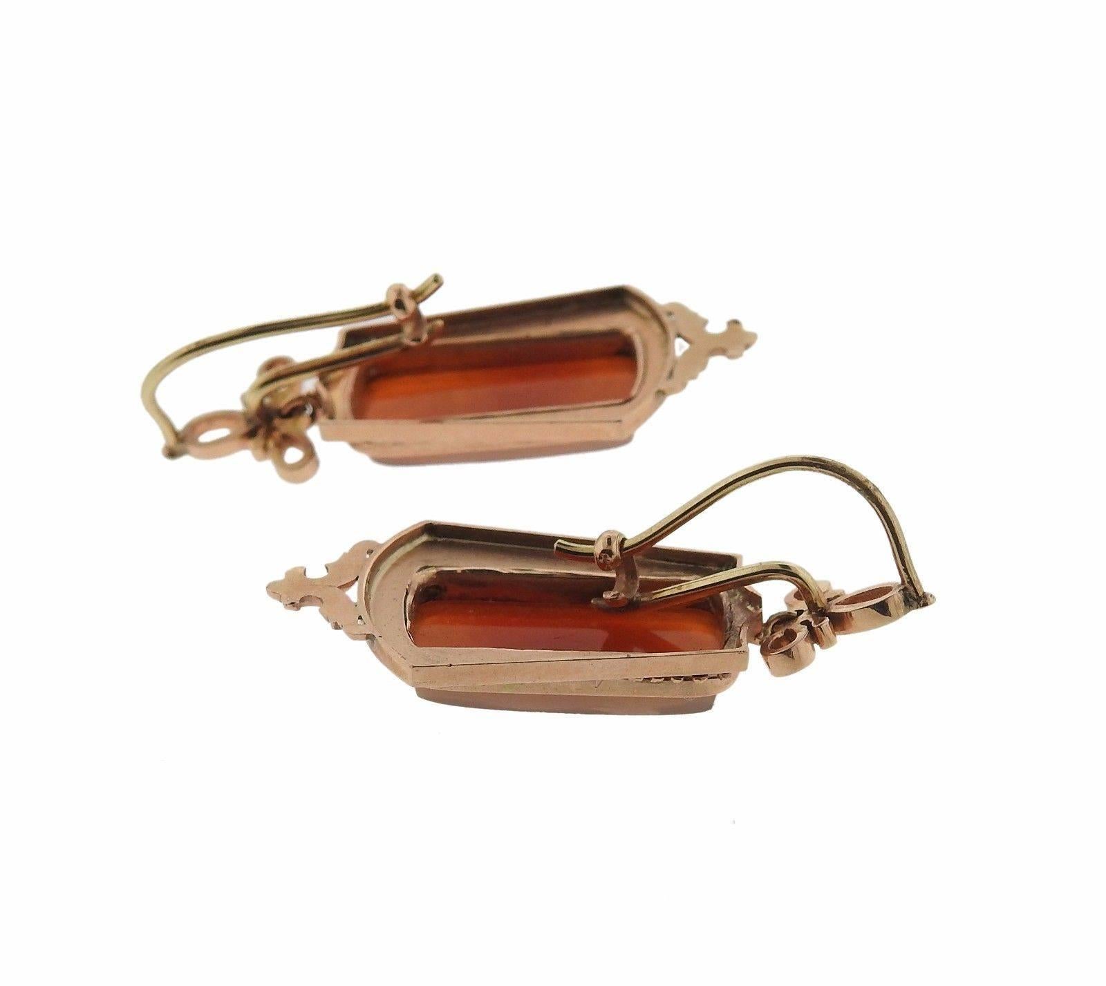 A pair of 14k rose gold earrings adorned with hardstone cameos.  The earrings are 39mm x 17mm and weigh 9.8 grams.