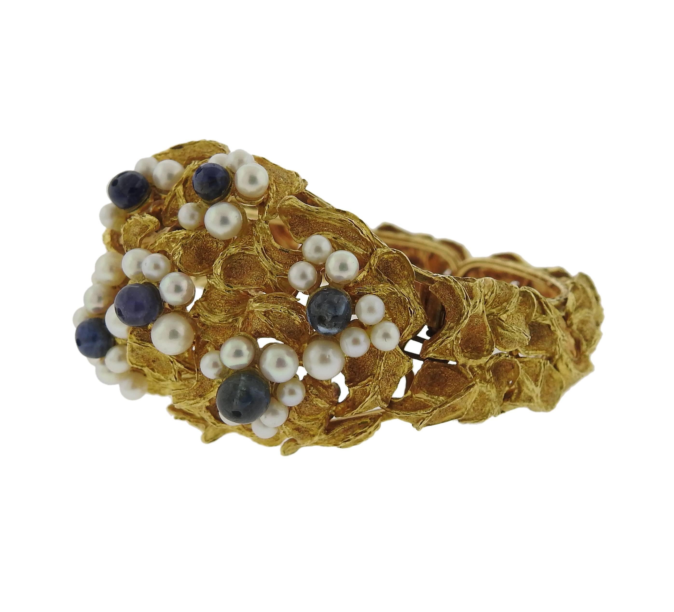 An 18k yellow gold bracelet, crafted by Green designer Ilias Lalaounis, featuring pearls and blue gemstones. Bracelet will fit up to 6 1/2" wrist and is 35mm wide at the widest point. Marked: A21, Greece, Maker's mark. Weight of the piece -