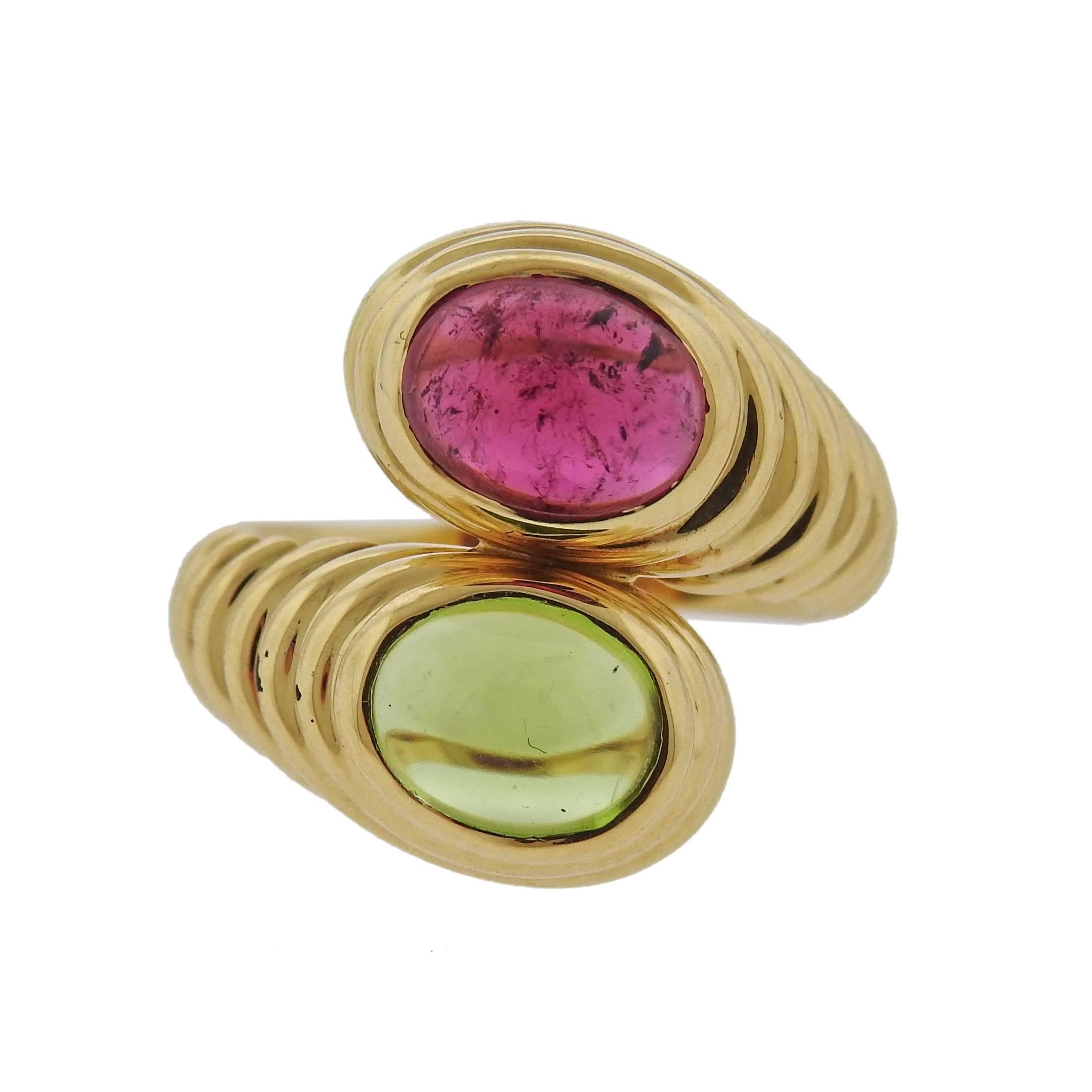 An 18k yellow gold bypass ring, crafted by Bulgari, set with pink tourmaline and peridot cabochons. Ring size 6, ring top is 20mm wide , ring weigs 13 grams. Marked: Bvlgari, 750, Italian mark 