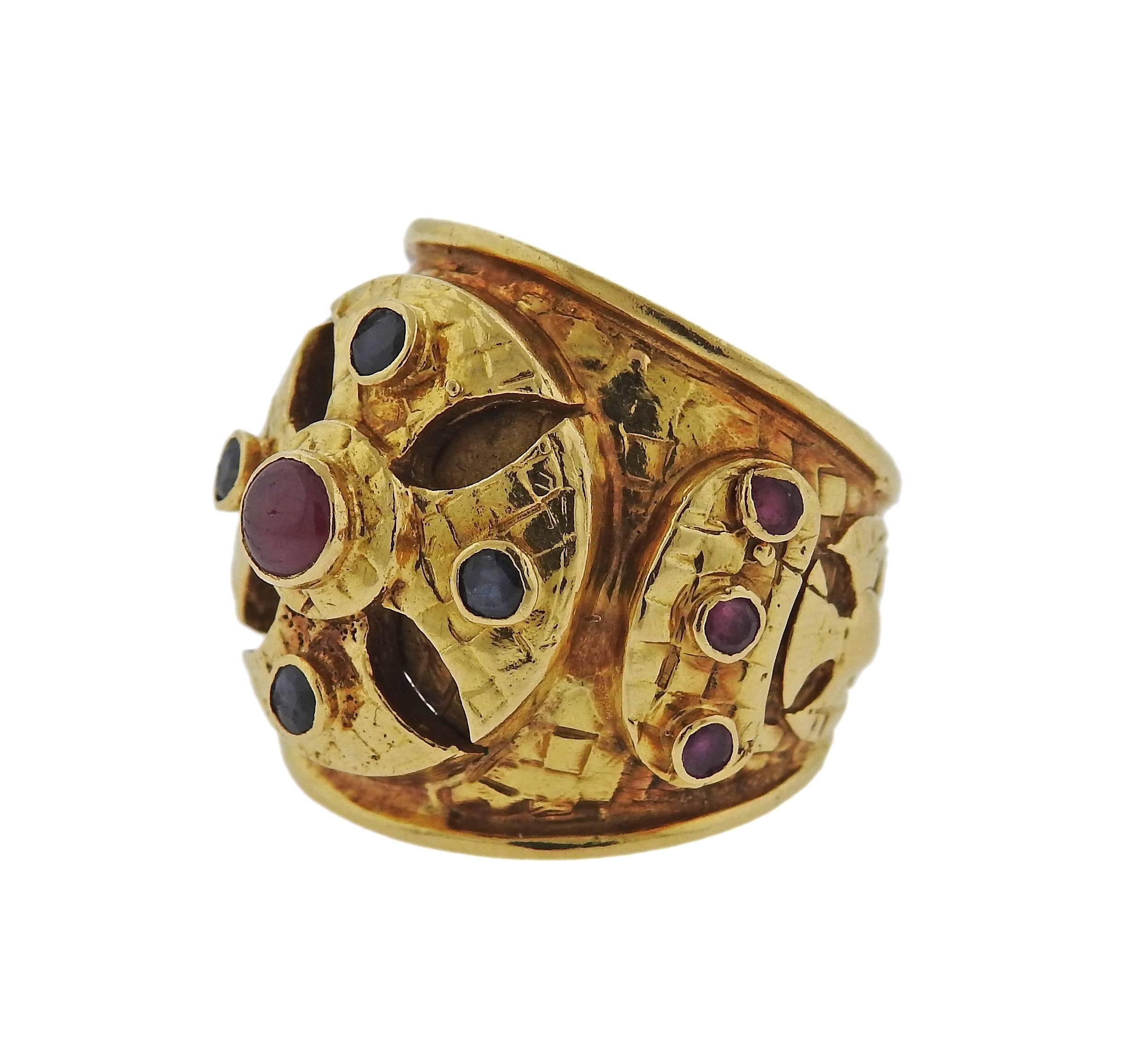 An 18k gold dome band ring featuring ruby and sapphires, crafted by Ilias Lalaounis. Ring is a size 6.5 and measures 23.2mm at widest point. Marked Ilias Lalaounis, Maker's Hallmark, A21, 750. Weight is 17.2 grams. 