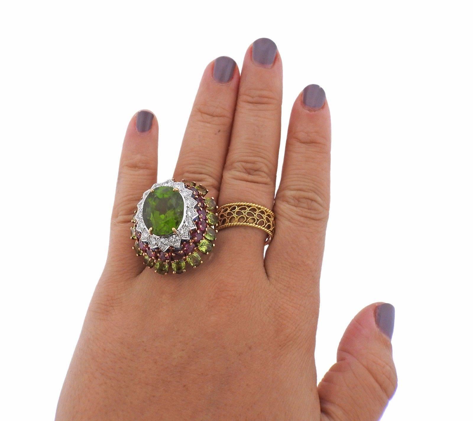 An 18k yellow gold ring set with a 13 carat peridot which is accented by sapphires, rubies, peridots and approximately 1.60ctw of GH/VS-SI1 diamonds.  The ring is a size 5 1/2, ring top is 30mm x 27mm, sits approx. 21mm from the top of the finger. 