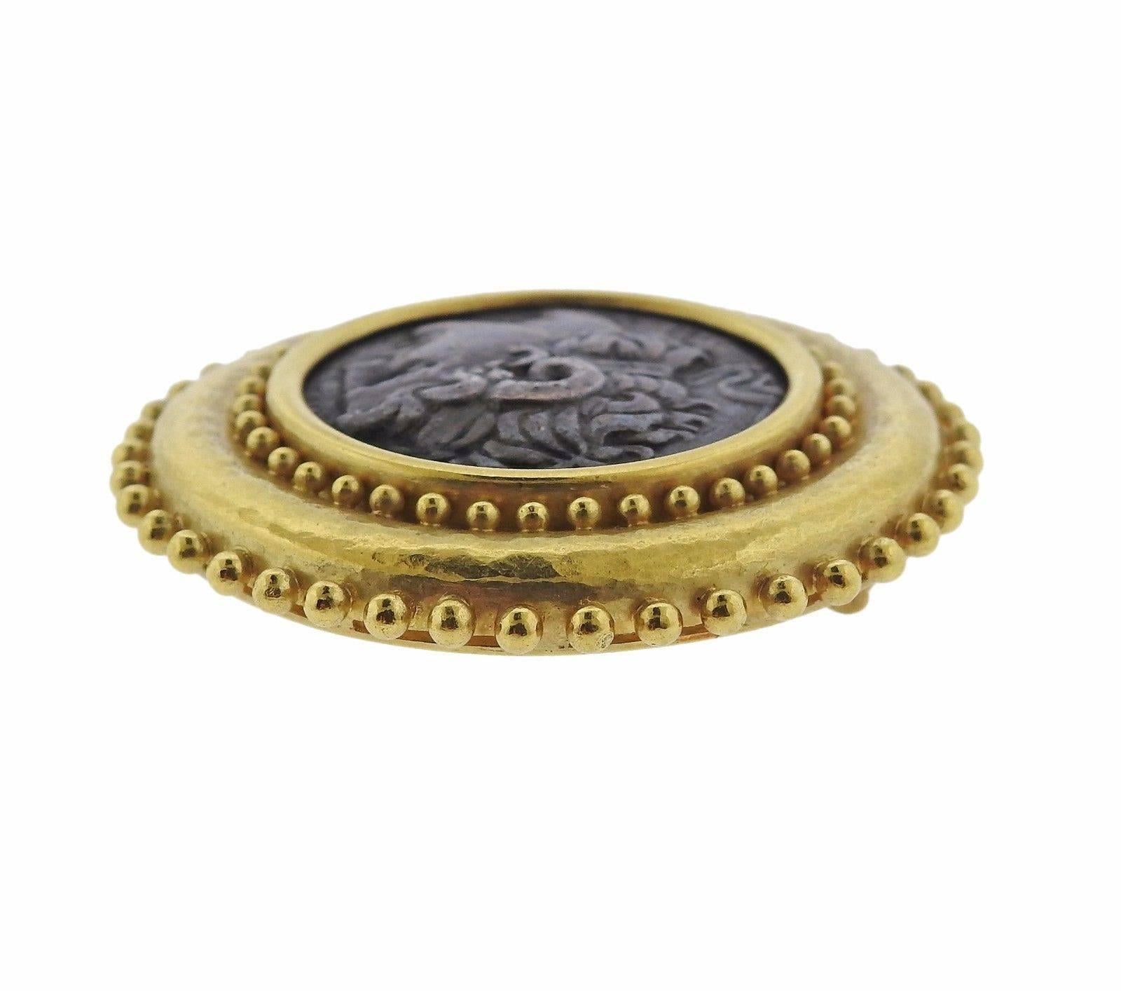 An 18k yellow gold brooch set with a bronze coin.  The brooch measures 47mm in diameter and weighs 44.1 grams.  Marked: Maker's Mark, 18k.