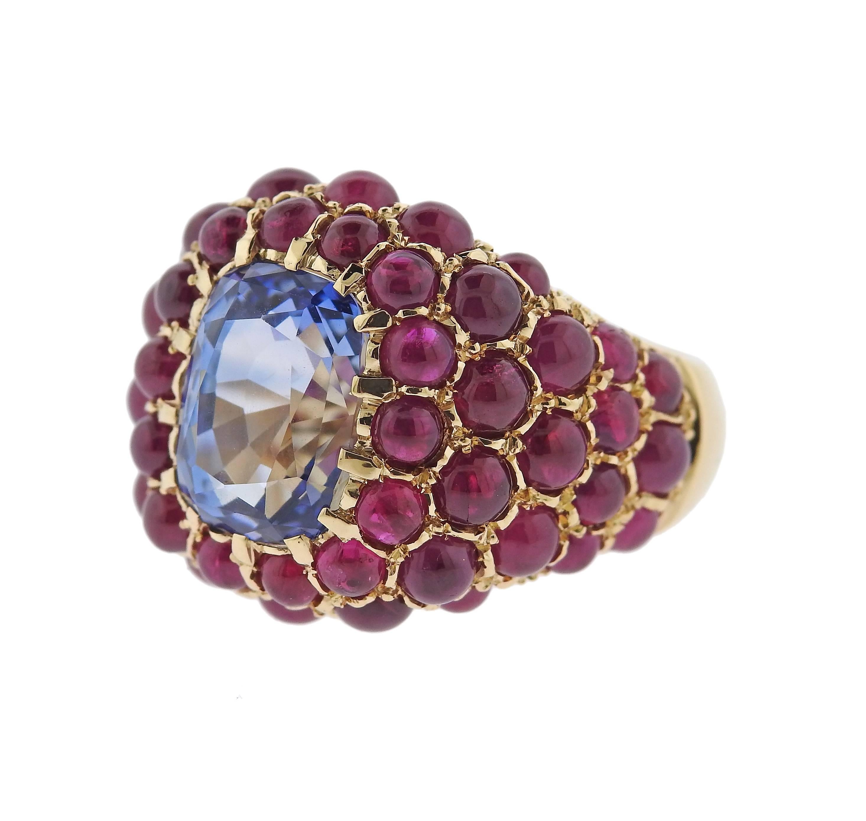 Impressive 18k yellow gold ring, crafted by Verdura, featuring an approximately 6.80ct blue sapphire in the center, surrounded with ruby cabochons.  Ring is a size - 7, ring top is 20mm wide. Marked: Verdura, 18k. Weight - 15.9 grams