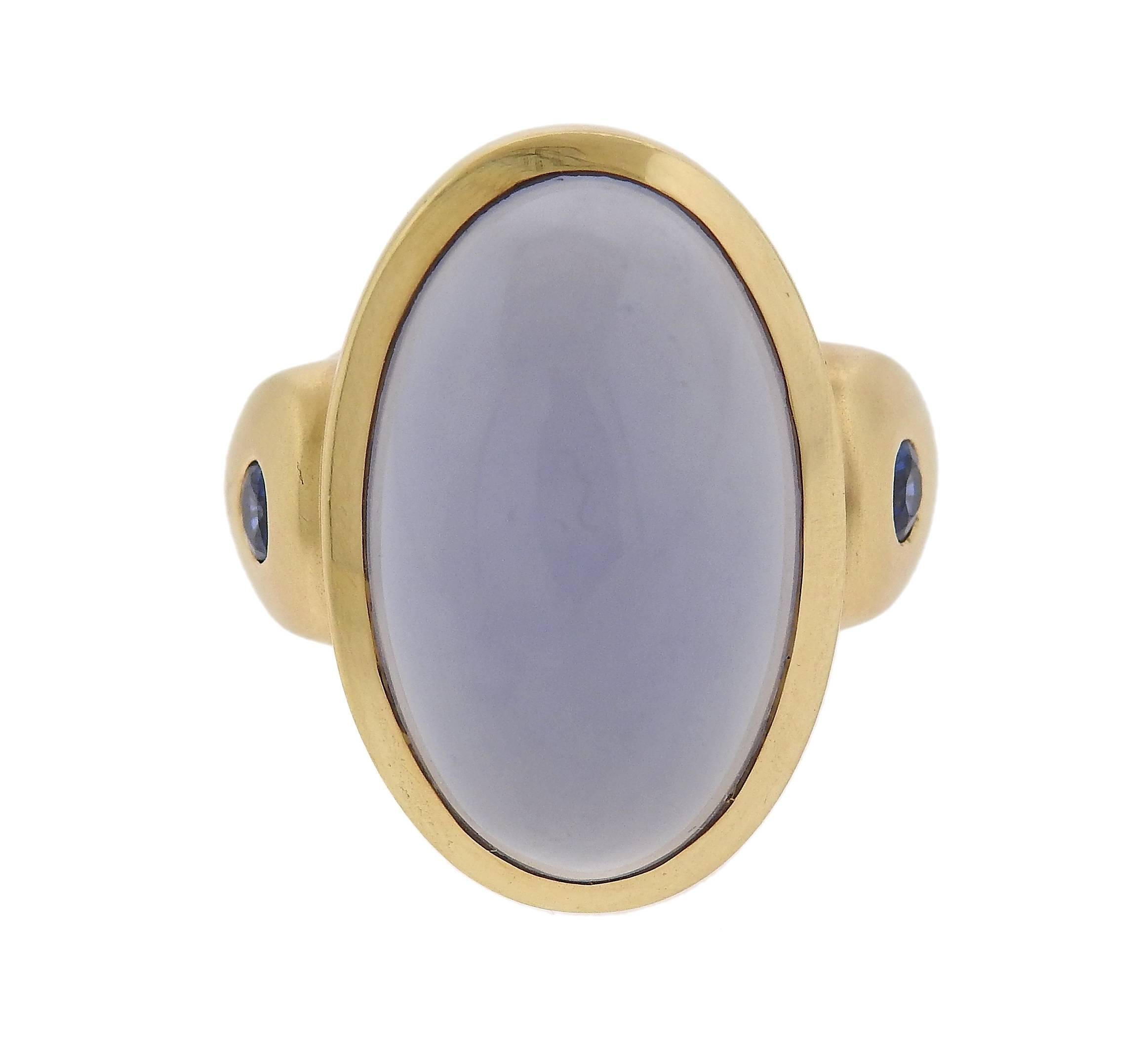 An 18k yellow gold ring, featuring an approximately 17ct chalcedony cabochon (measuring , set ith two sapphires on sides. Ring size 7, ring top is 23mm x 20mm. Weight - 16.6 grams.