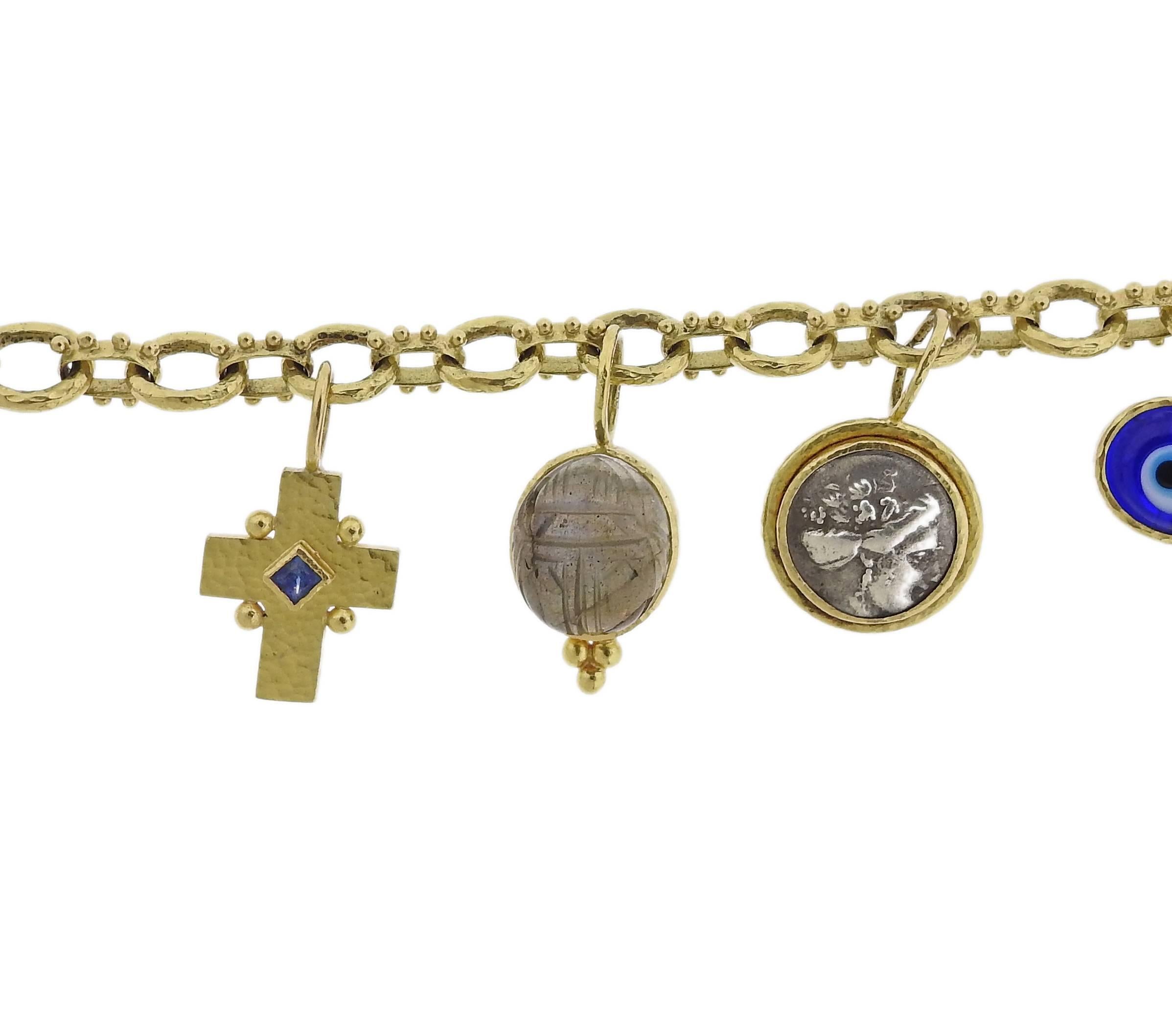 An 18k yellow gold toggle bracelet, crafted by Elizabeth Locke, featuring five charms: an evil eye, ancient coin, labradorite scarab, cross with a sapphire and Venetian glass intaglio. Bracelet is 8" long, charms approx. 22mm long. Marked: 18k,