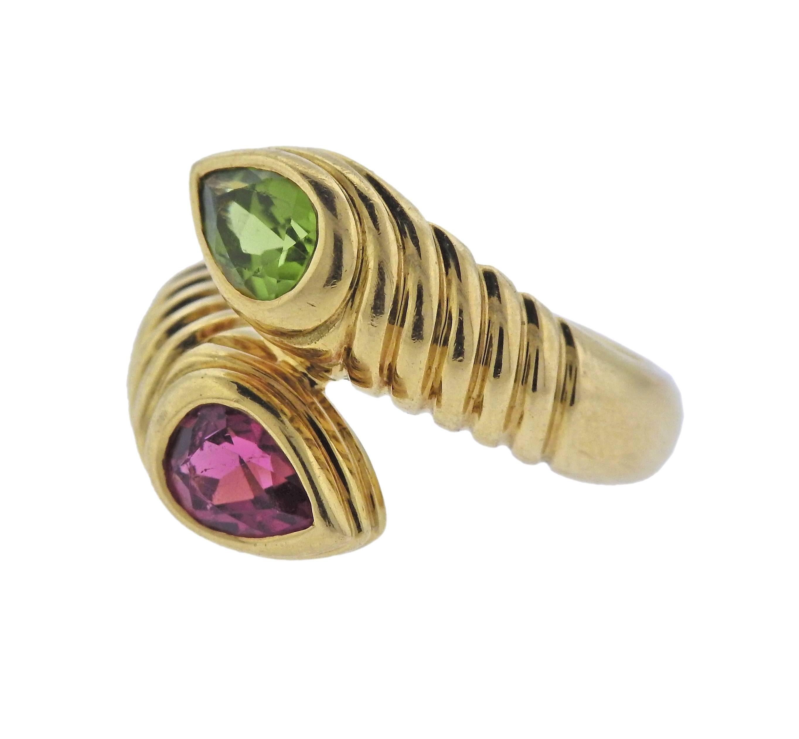 Lovely Bvlgari bypass ring set with pink tourmaline and peridot in 18K gold. Ring is a size 6 and measures 16mm at widest point. Marked with Bvlgari, 750, Made in Italy. Ring weighs 12.6 grams. 