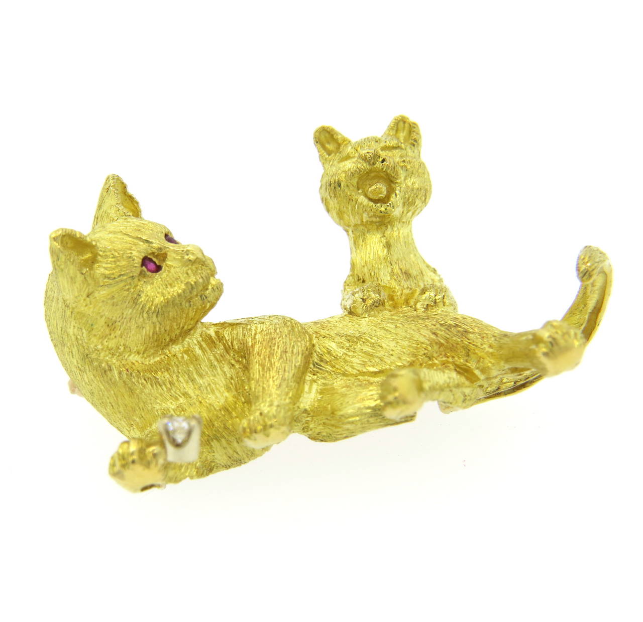An 18k yellow gold brooch depicting a cat and a kitten playing.  The cat features ruby eyes and a G/VS diamond weighing approx. 0.05ctw.  The brooch measures 37mm x 25mm and weighs 14.6 grams.