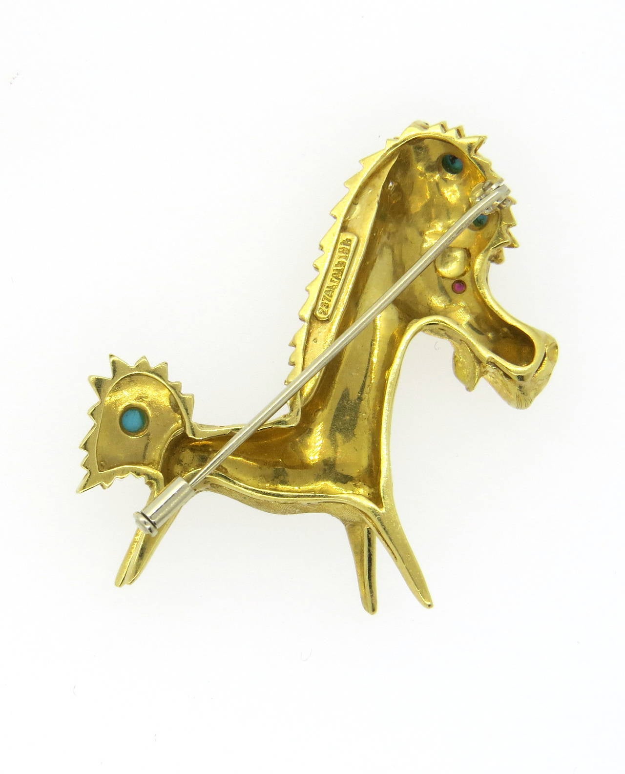 An 18k yellow gold brooch depicting a donkey, set with a ruby eye and turquoise cabochons.  The brooch measures 45mm x 45mm and weighs 15.7 grams. Marked: 237AL, Italy, 18k.