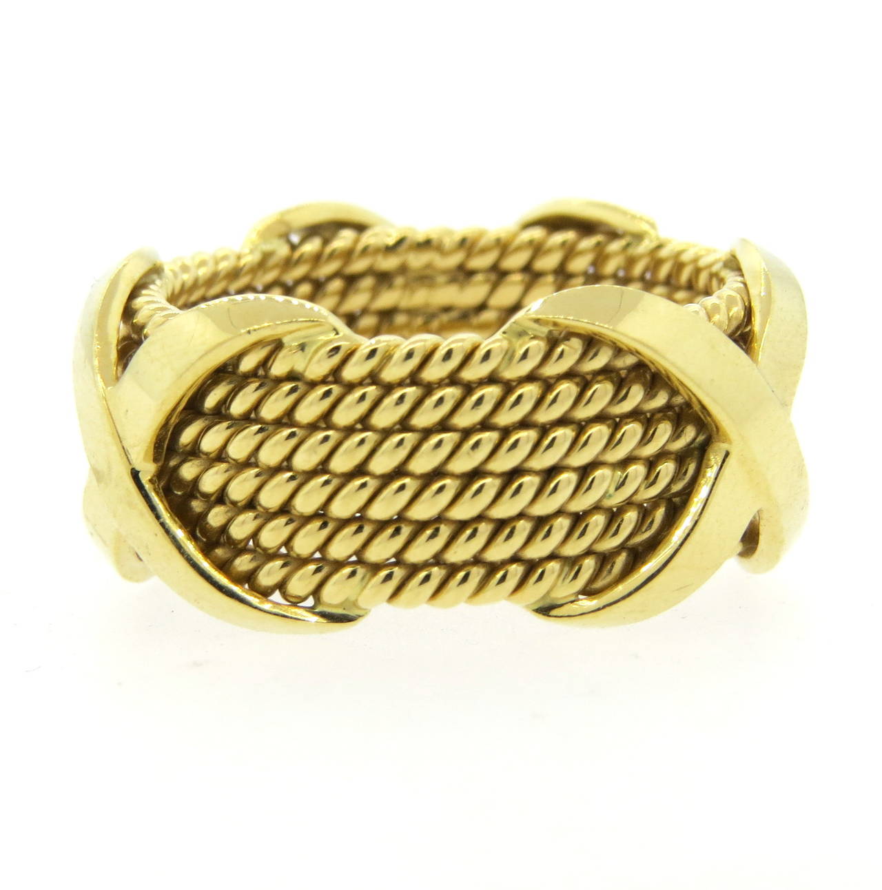 An 18k yellow gold band ring in a rope motif with x stations.  Crafted by Jean Schlumberger for Tiffany & Co., the ring is a size 9.5 and has a width of 12mm.  The ring weighs 16.4 grams.  Marked Tiffany & Co, Schlumberger Studios, 750