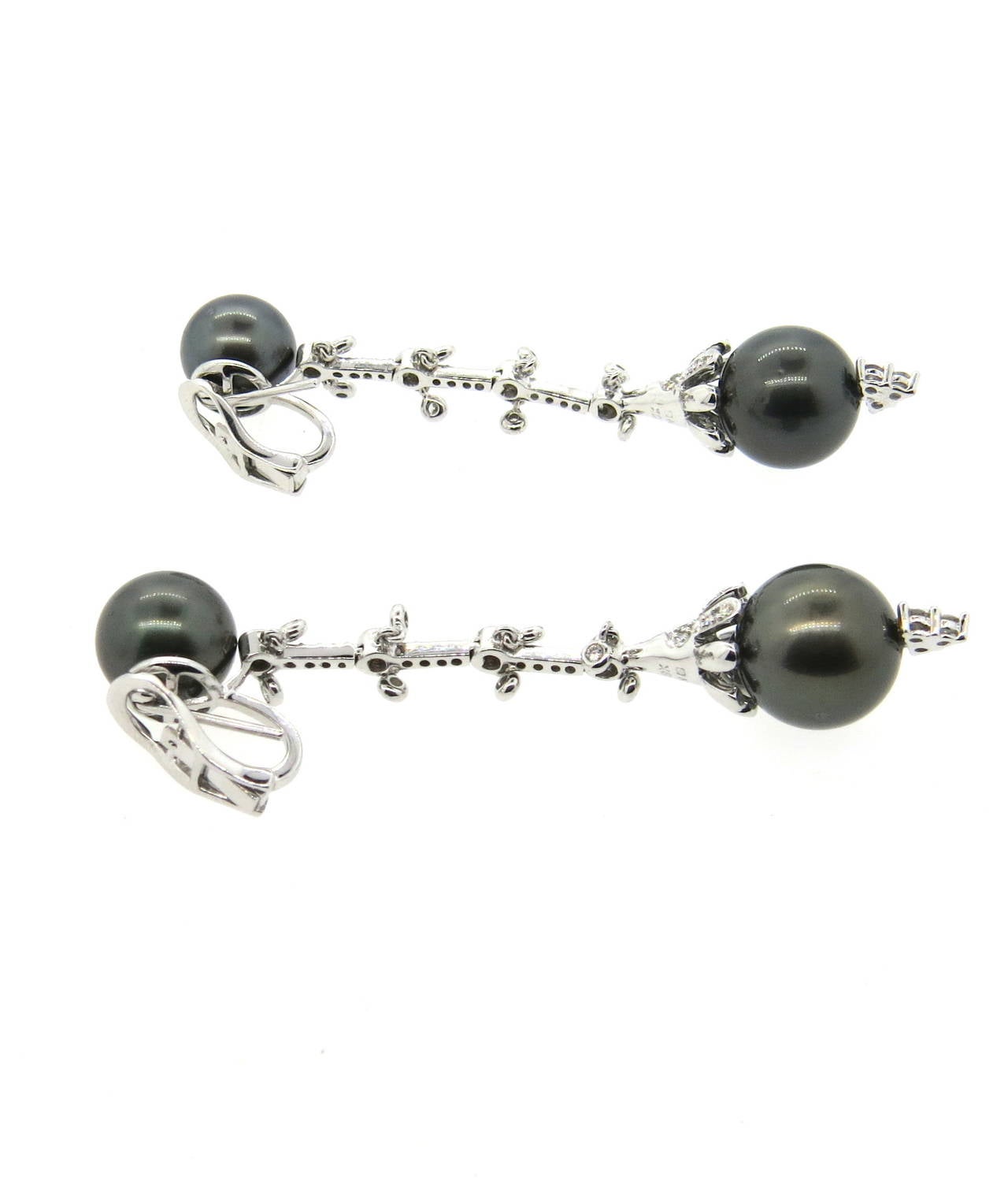 Beautiful 18K white gold long drop earrings featuring Tahitian pearls and decorated in approximately 0.80-0.90ctw of diamonds. Pearls measure 10.9mm and 12.8mm in diameter. Earrings measure 68mm long. Weigh 20.5 grams.