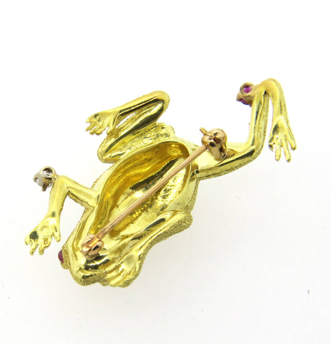 An 18k yellow gold frog pin set with ruby cabochons for eyes, and a round cut ruby on the back leg.  The piece is also adorned with a G/VS diamond weighing approximately 0.06cts.  The piece measures 38mm x 27mm and weighs 11.8 grams.