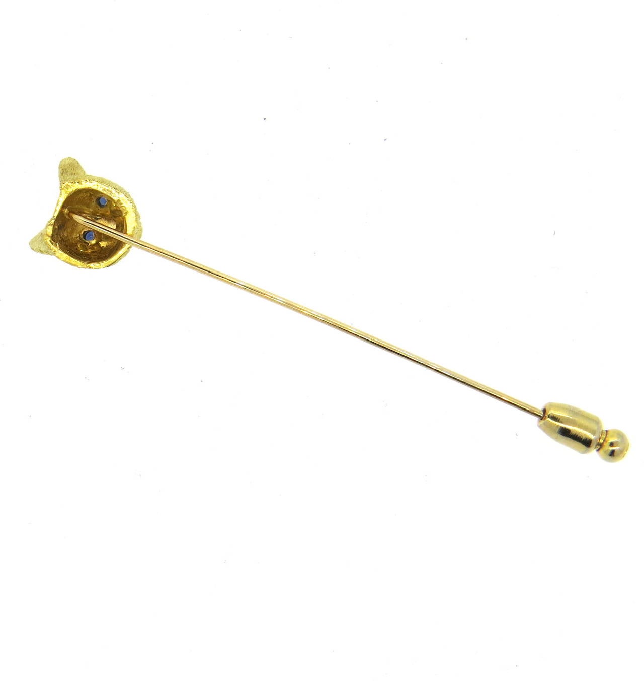 An 18k yellow gold stick pin depicting a cat with sapphire eyes.  The pin measures 10.6mm x 10.5mm and weighs 4.0 grams.