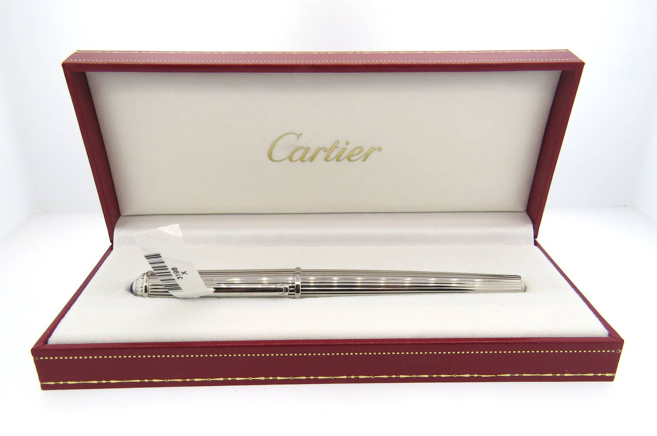 Brand new, store sample, Cartier Diabolo platinum finish fountain pen. Pen measures 142mm long and features a jeweler's sapphire on the cap. Pen is marked Cartier, 020084. Reference number ST180016. Pen comes with original box, booklets and 10