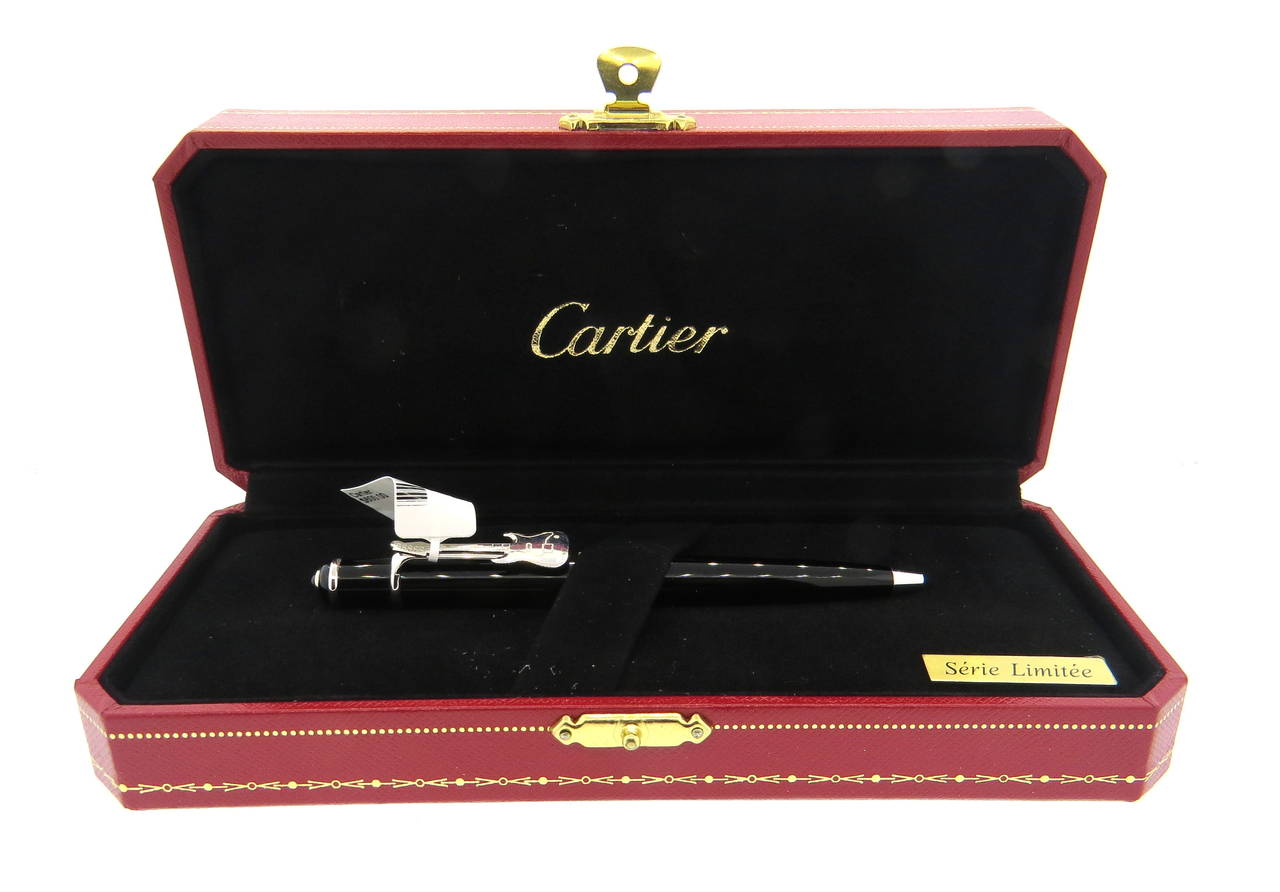 Limited Edition Cartier Mini Diabolo Rock n' Roll ball point pen featuring black lacquer, platinum finishes and guitar. Pen measures 115mm long, features a jeweler's ruby on the top. Pen is a brand new, in store sample, comes with original box and
