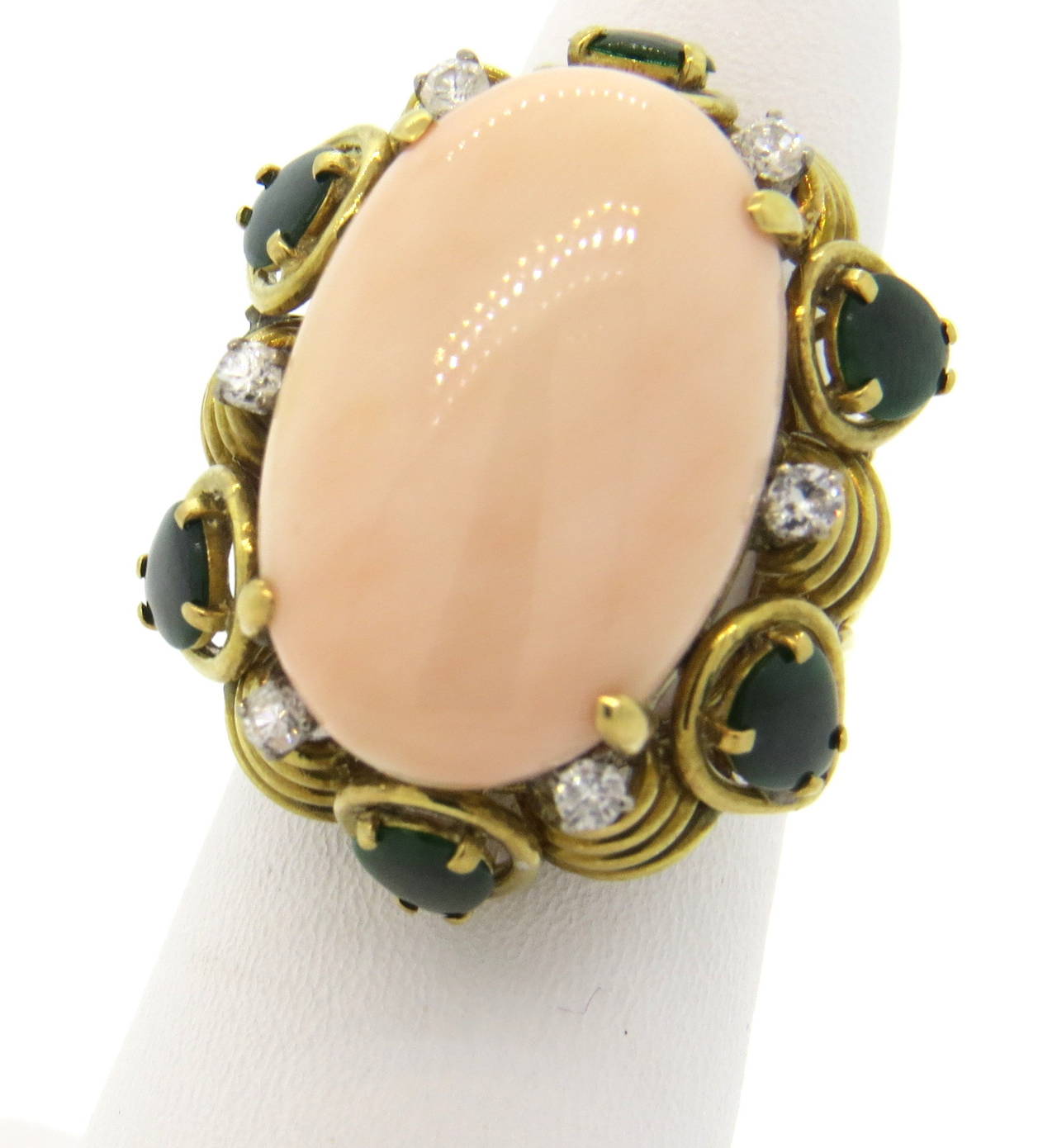 An 18k yellow gold ring set with a coral cabochon (22mm x 14mm) surrounded by approximately 0.24ct of G-H/VS -SI diamonds and pair shaped jade.  The top of the ring measures 29mm x 23mm and sits 15mm from the finger.  The ring is a size 5 1/2 and