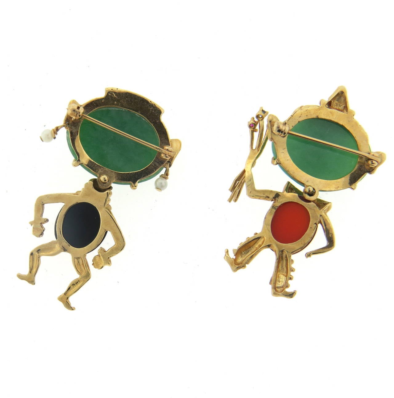 A pair of 14k yellow gold brooches set with multi colored jade and pearls.  Brooches measure 43mm x 23mm and 43mm x 32mm respectively.  One of the figures is depicted holding flowers containing rubies and a sapphire. The total weight of the set is