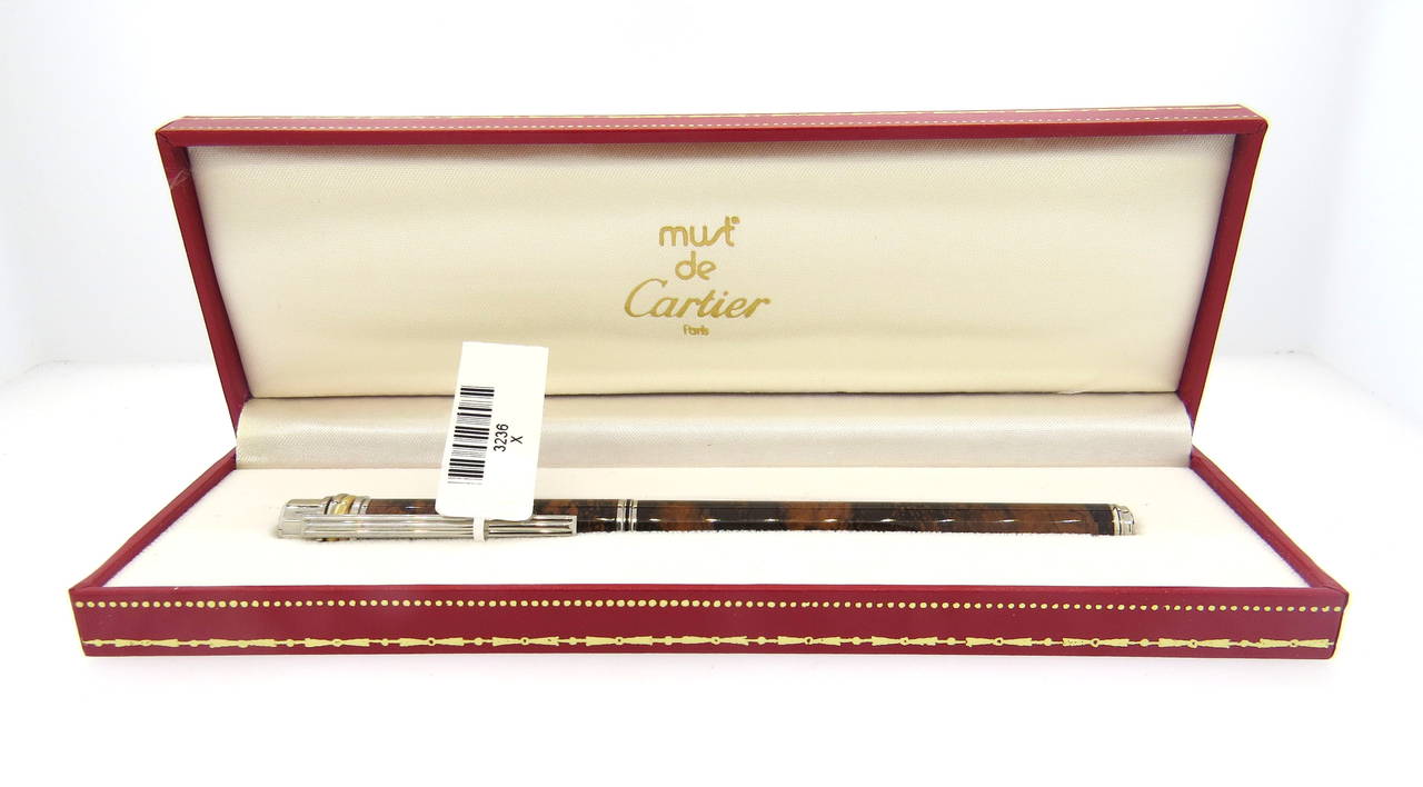 Slim Cartier Noveau Must fountain pen featuring a brown marble like lacquer design. Pen measures 138mm, features an 18K gold nib. Pen is a brand new, in store sample, comes with original box booklets and two cartridges. Pen has light tarnish from