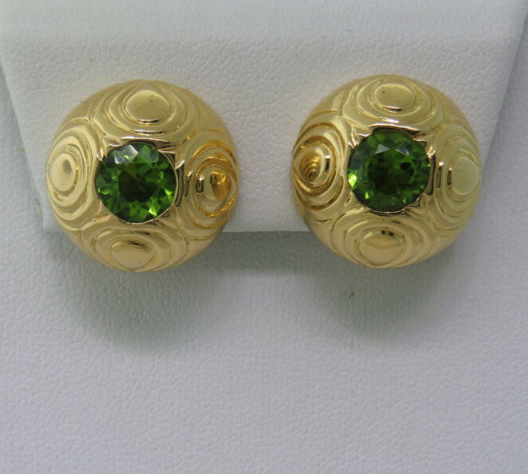 18k gold earrings by Gumps, featuring 7.4mm peridot gemstones in the center. Earrings are 19.2mm in diameter. Weight is 18.9 gr.