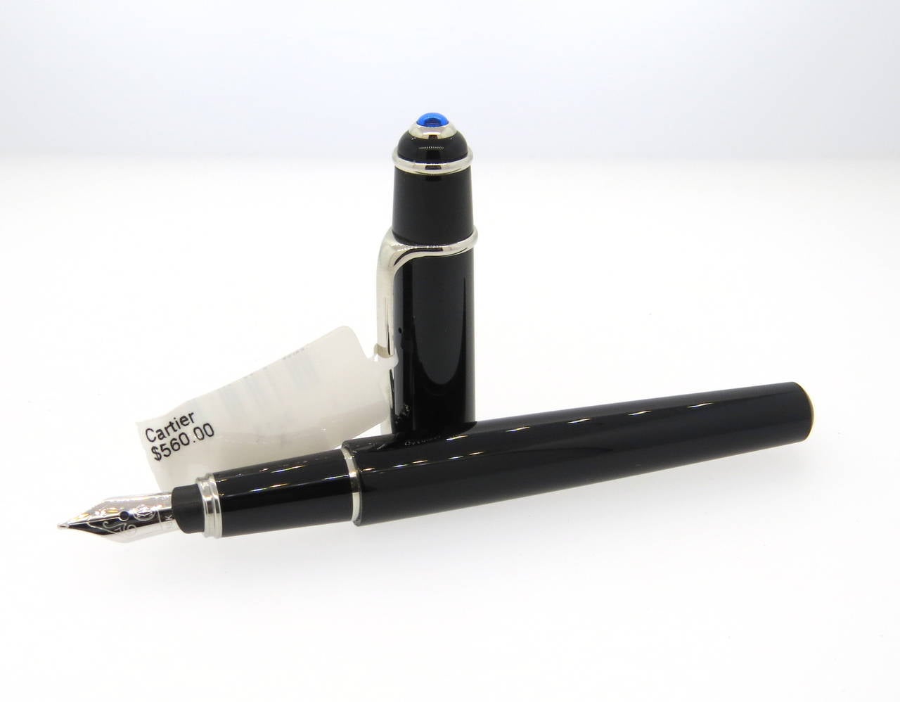 Durable Cartier Mini Diabolo fountain pen featuring a smooth black composite exterior with platinum finishes and an 18K gold nib. Pen measures 118mm and is accented by a jeweler's sapphire on the pen cap. Pen is a brand new in store sample. Comes