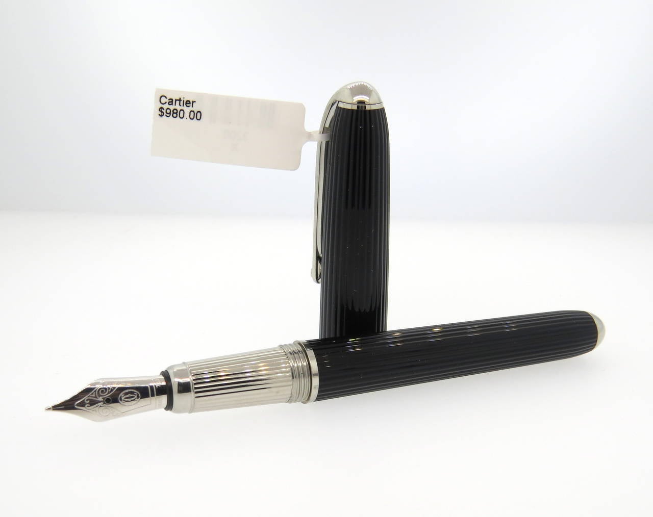 Beautiful Cartier fluted black composite fountain pen featuring platinum plated finishes and an 18K gold nib. Pen measures 145mm long. Pen is a brand new in store sample, comes with original box, booklets and cartridges. Pen retails for $980.