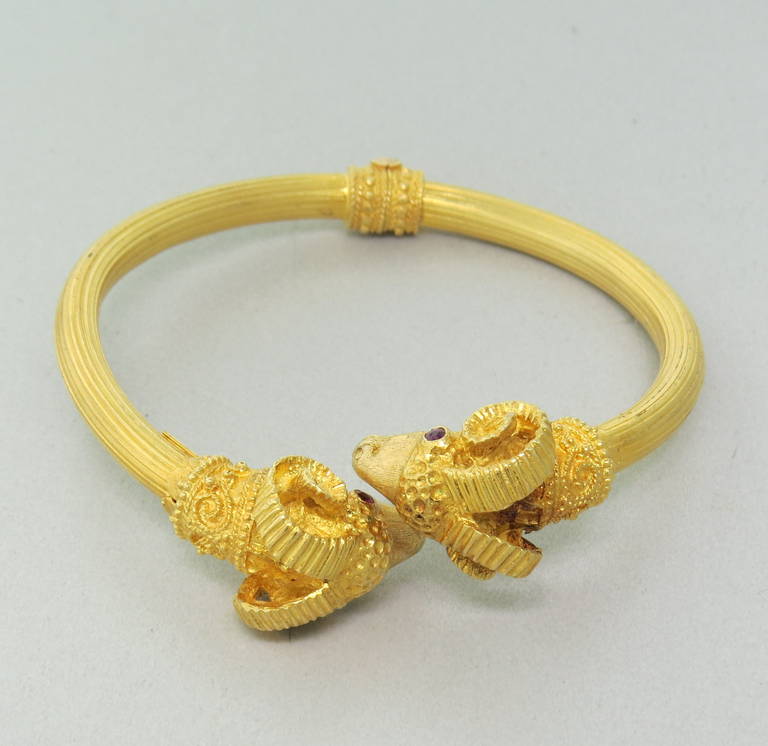 Ilias Lalaounis bracelet in 18k yellow gold,featuring two ram's heads with ruby eyes. Bracelet will comfortably fit up to 5 1/2