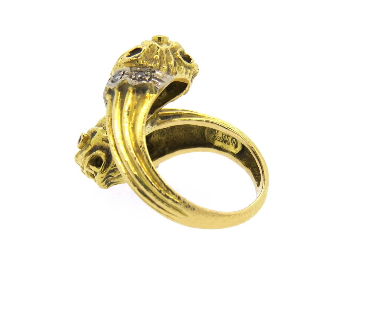 18k gold bypass ring, crafted by Ilias Lalaounis, set with diamonds and ruby eyes. Ring is a size 7, ring top is 23mm wide. Marked Greece, Makers mark and 750. Weight of the piece - 13.8 grams