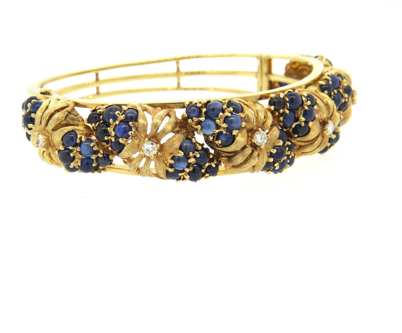 Mid century 14k gold bangle bracelet, set with blue sapphire cabochons and approx. 0.30ctw in diamonds , organized in floral design. Bracelet will fit up to 7 1/2