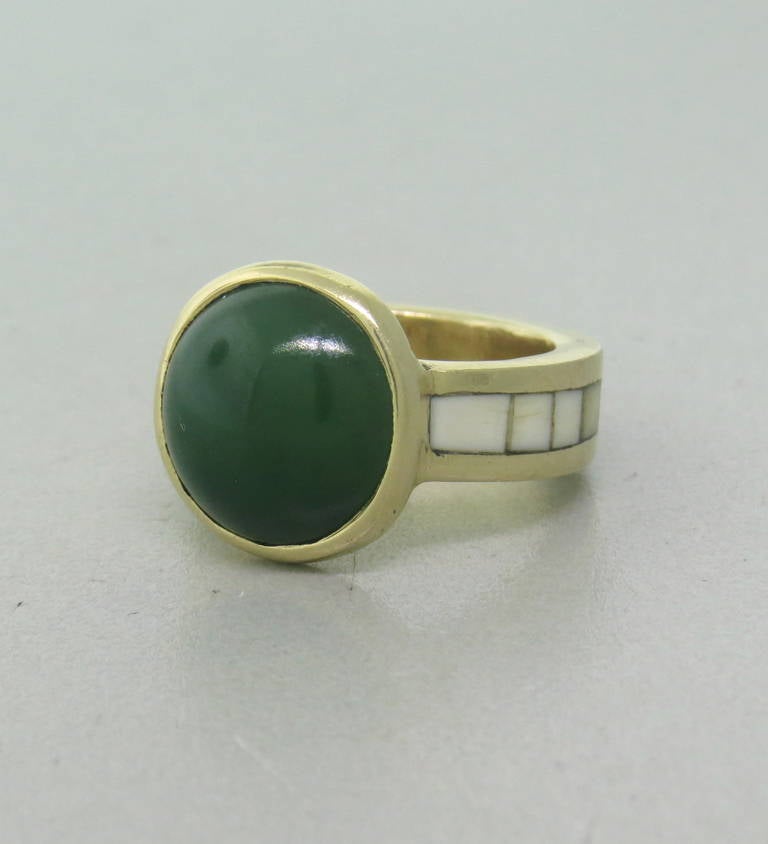 A vintage 14k yellow gold ring by Theodore Drendel.  The ring is set with a 13mm Jade Cabochon and a white hardstone inlay around the 6mm wide shank.  The ring is a size 7 and weighs 12.6 grams.