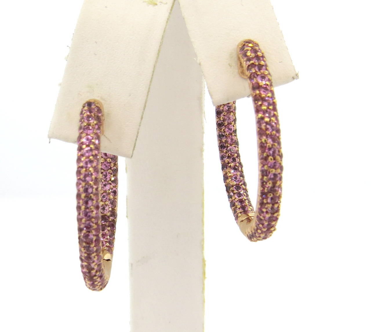 18k rose gold hoop earrings,  decorated with inside out set 4.77ctw pink sapphires. Earrings measure 32mm in diameter and 3.3mm wide. Marked S 477, 18k 750. Weight - 12.4 grams