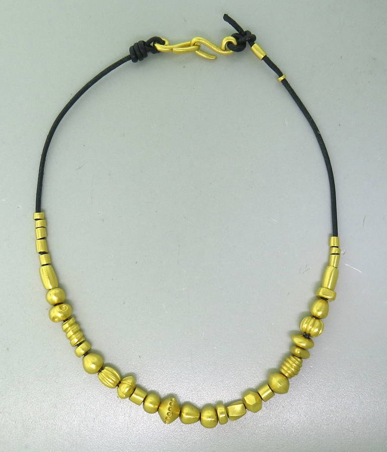 22k yellow gold slide charm necklace by Linda Lee Johnson on a leather cord with gold hook clasp. Necklace is 17
