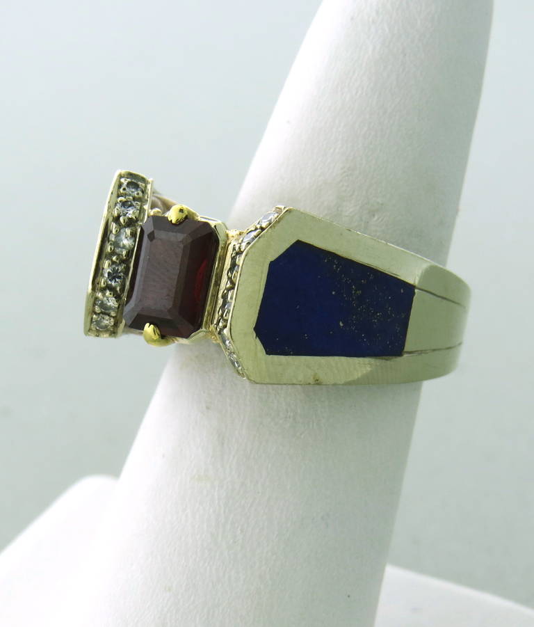 An ornate 14k and 18k gold ring with lapis inlay on the sides of the ring with approx. 0.12ctw in diamonds and an emerald cut garnet weighing approximately 1.60ct.  The ring is a size 6 and weighs 12.6 grams.