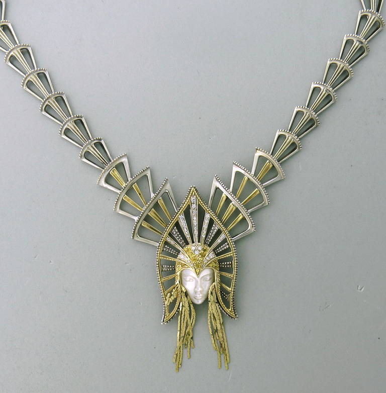 A 14k gold and sterling silver convertable brooch pin and necklace by world famous artist Erte (Romain de Tirtoff).  The necklace contains approx 0.25ct in diamonds and is also set with yellow sapphires and a carved mother of pearl face.  The