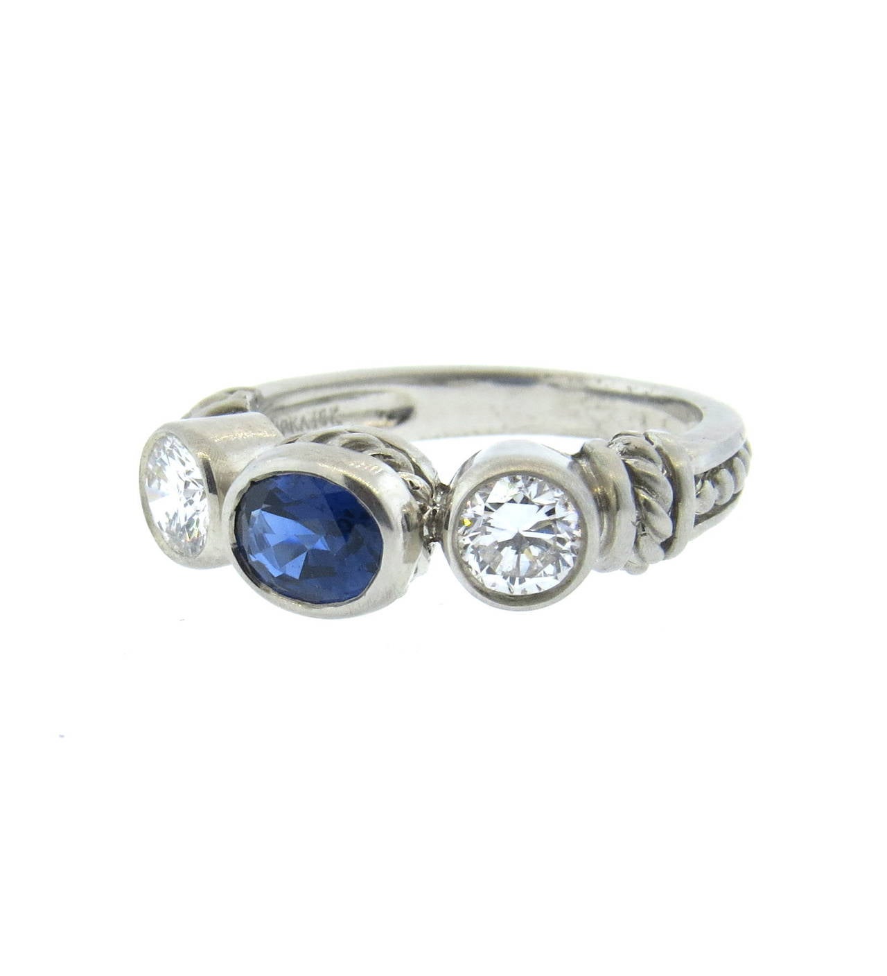 18k white gold ring by Judith Ripka, featuring oval sapphire, set with two diamonds on each side. Ring size is 6 1/2, ring top is 7mm x 20mm. Marked Judith Ripka and 18k. weight - 6.8 grams