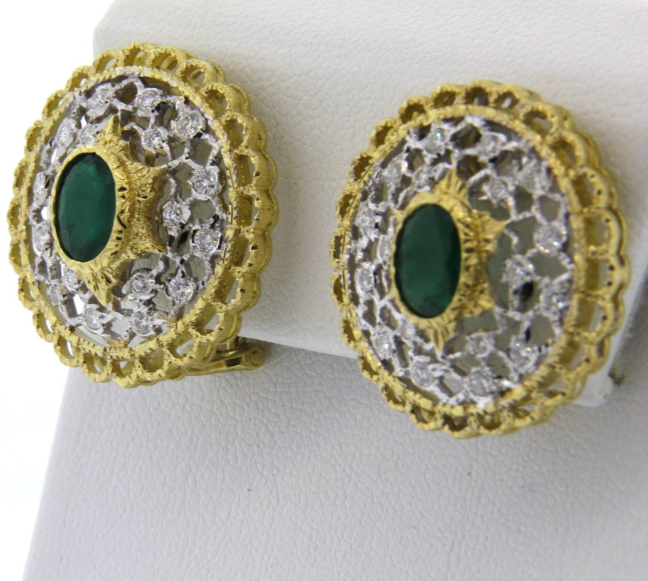 A pair of intricate 18k yellow and white gold earrings set with approx. 0.40ctw in diamonds and two emeralds approx. 1.66ctw.  Crafted by Mario Buccellati, the earrings measure 25mm in diameter and weigh 15 grams.