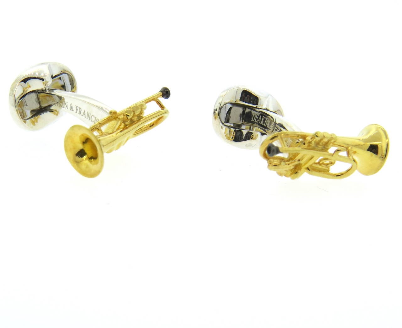 A pair of sterling silver cufflinks coated with gold enamel depicting trumpets.  Crafted by Deakin & Francis, the cufflinks measure 21mm x 10mm and weigh 12.8 grams.