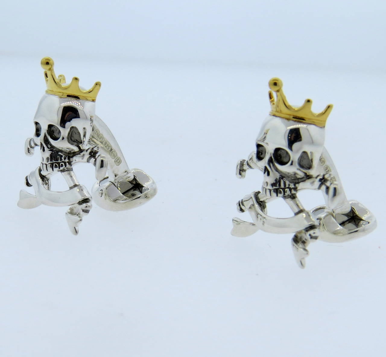 A pair of sterling silver cufflinks with gold enamel depicting skulls wearing crowns atop crossbones.  Crafted by Deakin & Francis, the cufflinks measure 28mm x 22mm and weigh 19 grams.