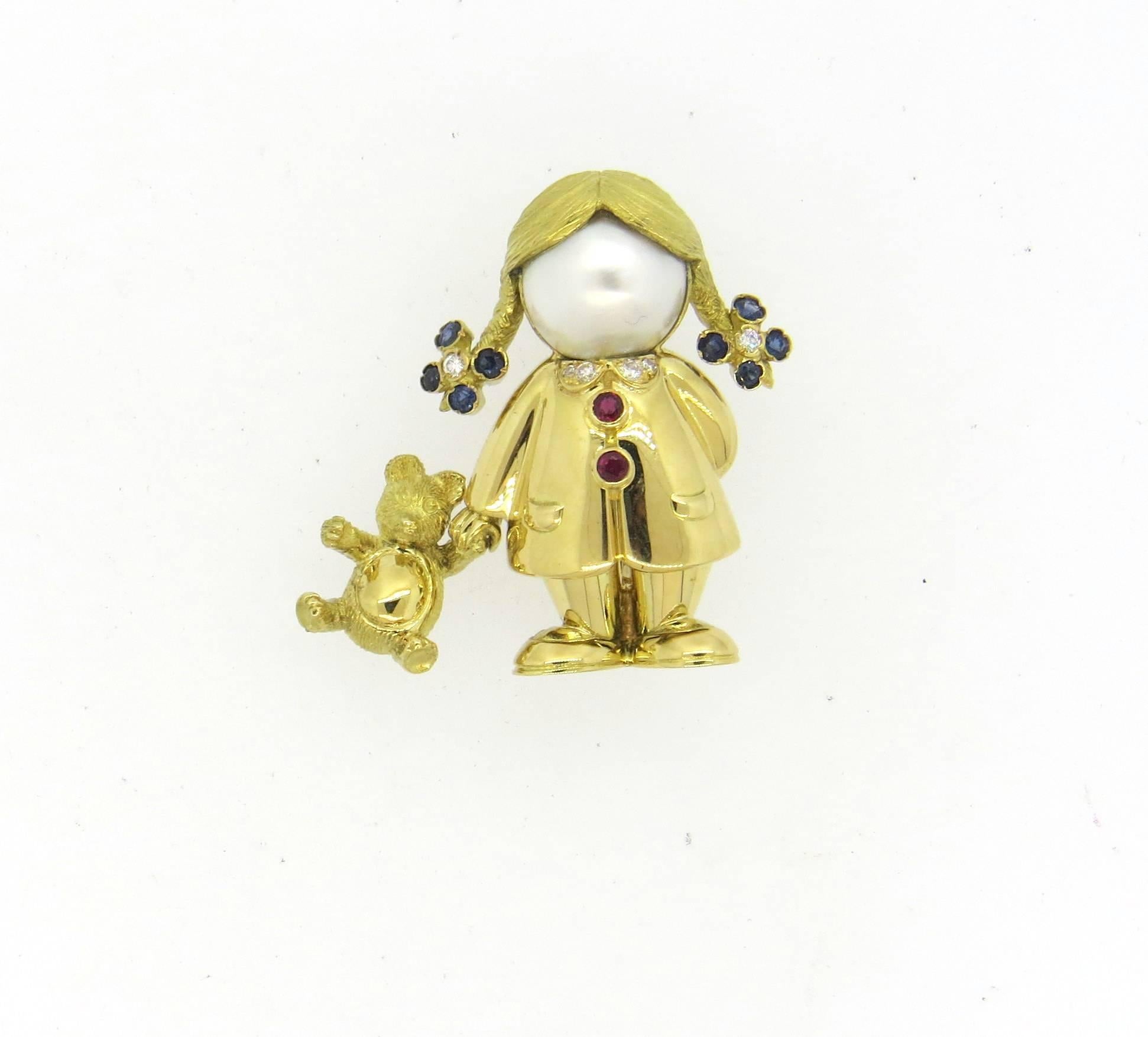 Adorable 18k gold brooch, crafted by Fred Paris, depicting a girl hold a teddy bear, decorated with diamonds, sapphires, rubies and mabe pearl. Brooch measures 30mm x 27mm. Marked: Fred Paris, or750. Weight of the piece - 15.4 grams 