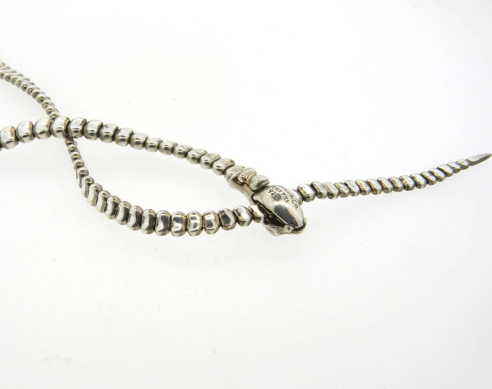 A sterling silver necklace in a snake motif.  Crafted by Elsa Peretti for Tiffany & Co., the length of the piece from end to end - 19 7/8