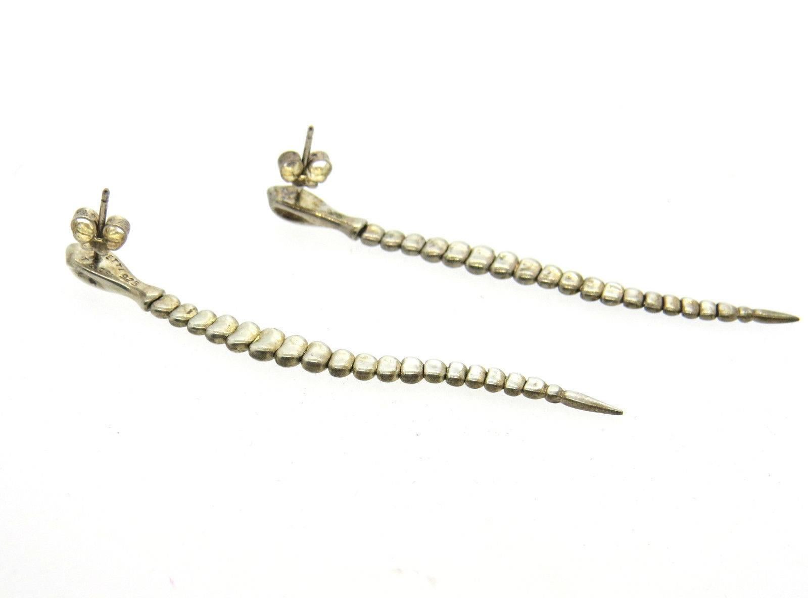 A pair of sterling silver earrings depicting snakes.  Crafted by Elsa Peretti for Tiffany & Co., the earrings are 71mm long and 5.4mm wide.  Marked: T & Co, 925, Peretti.  The weight of the earrings is 7.4 grams.